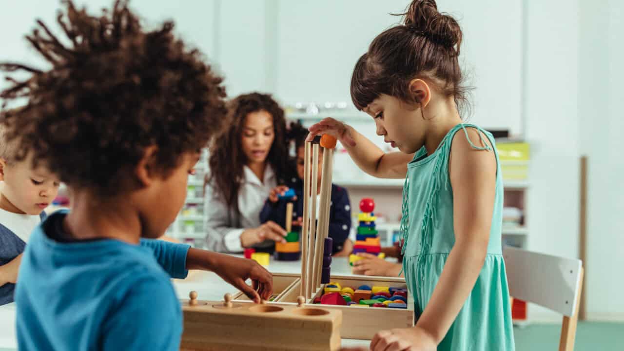 A group of children playing with wooden blocks in a classroom.