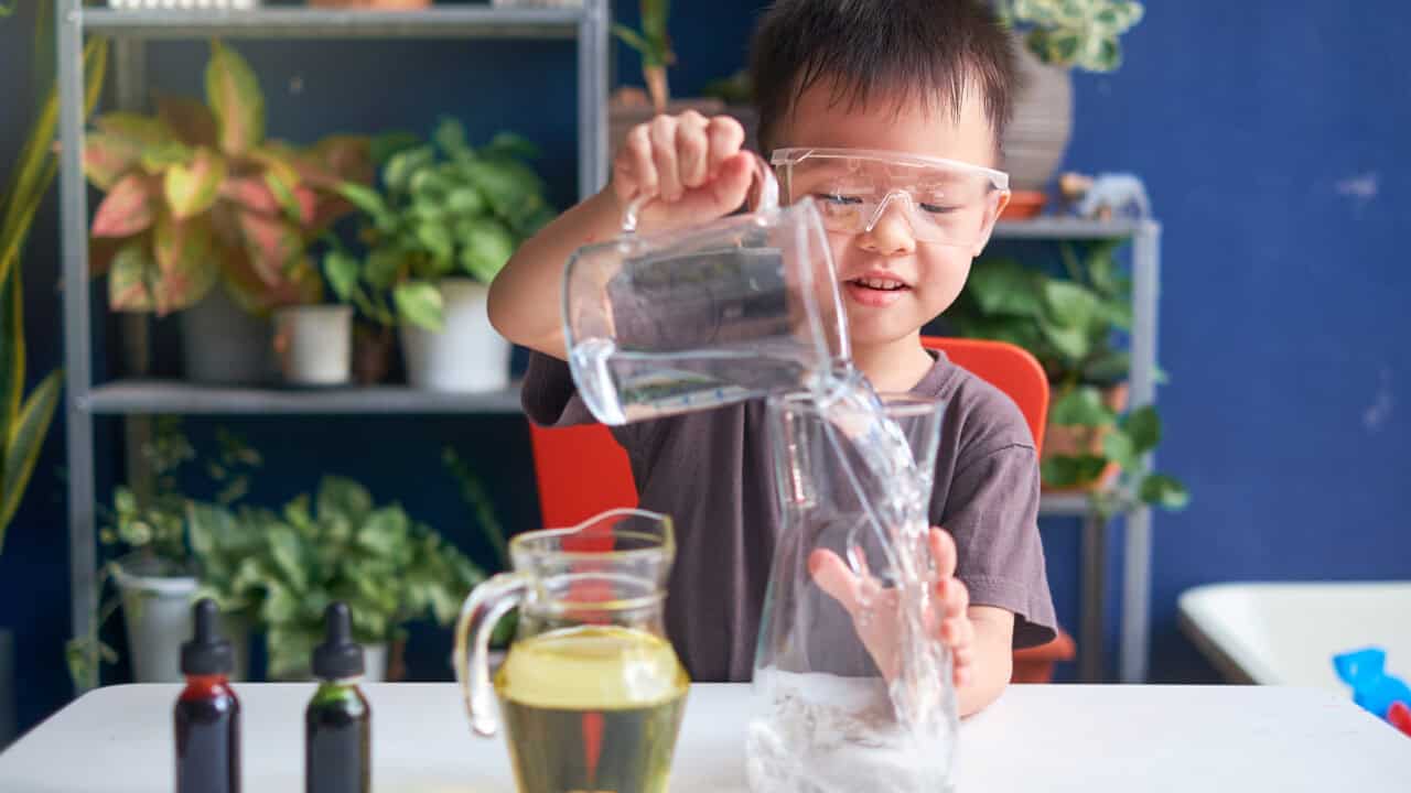 A young boy is pouring liquid into a glass.