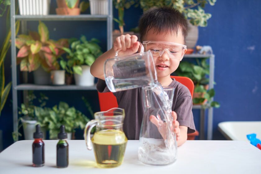 A young boy is pouring liquid into a glass.